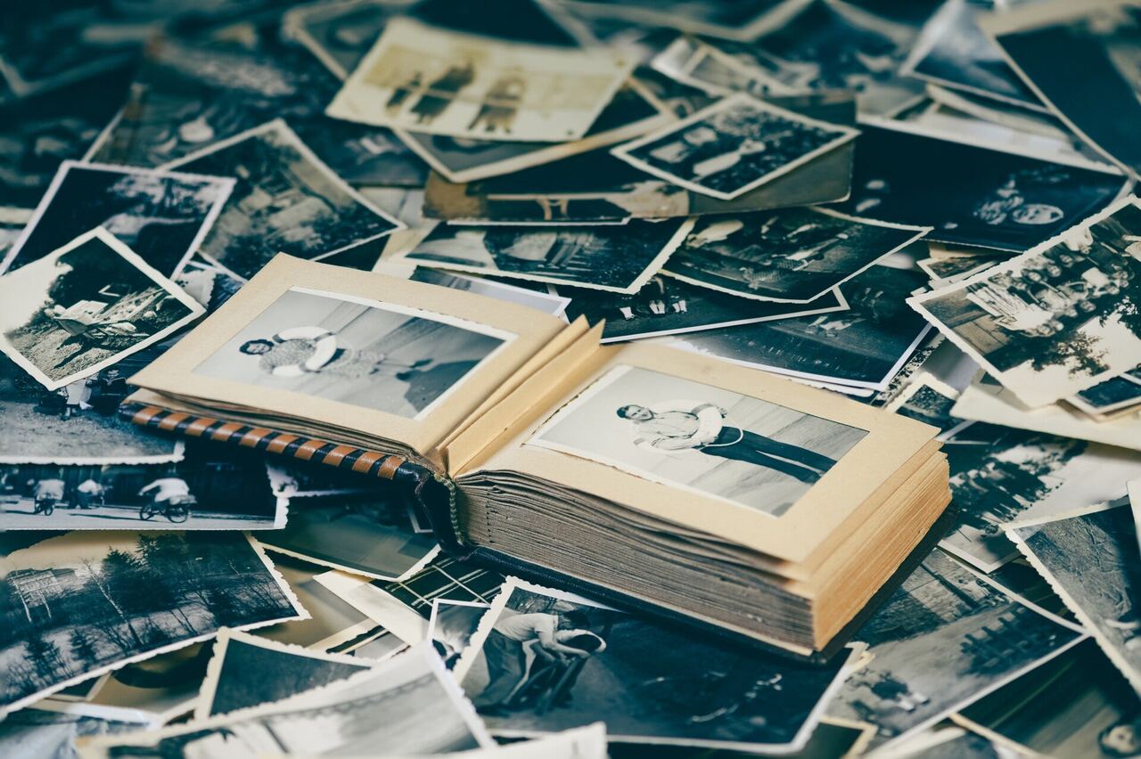 An open family album lying on a heap of old black-and-white photographs